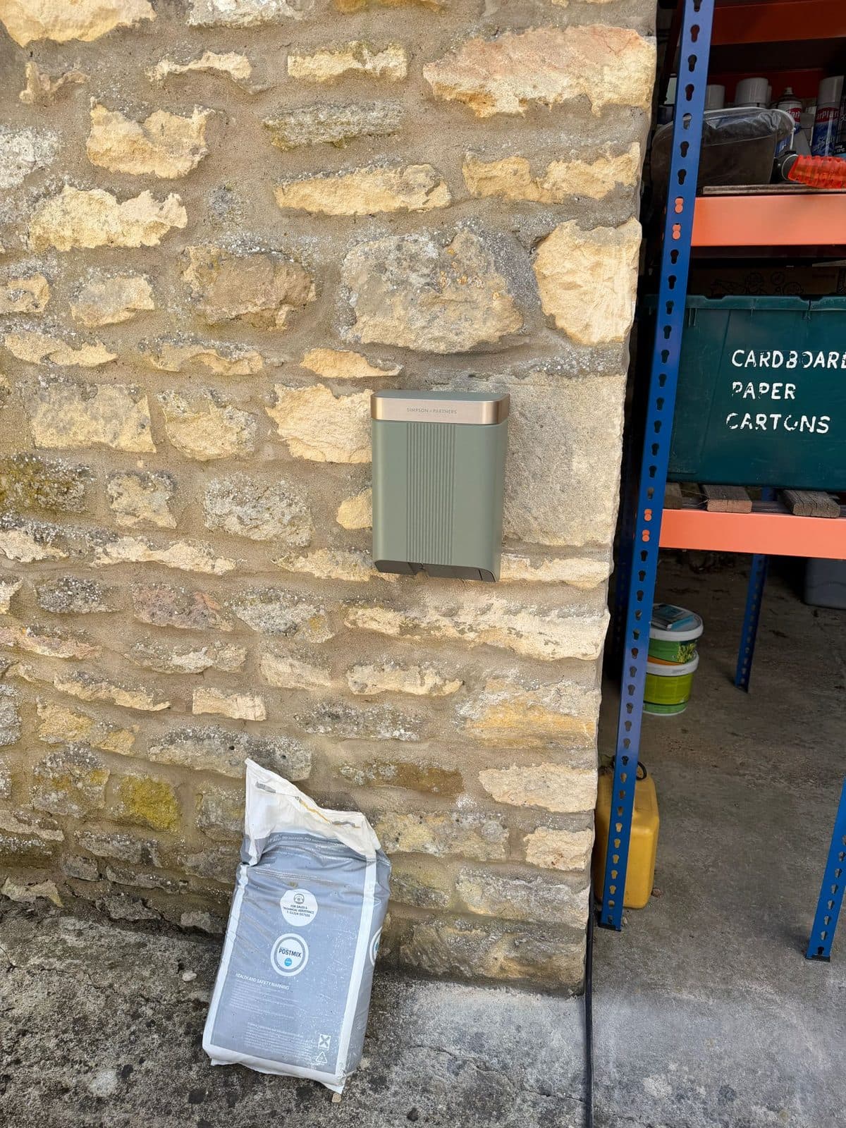Sage-green Simpson & Partners EV charger fitted to a stone wall