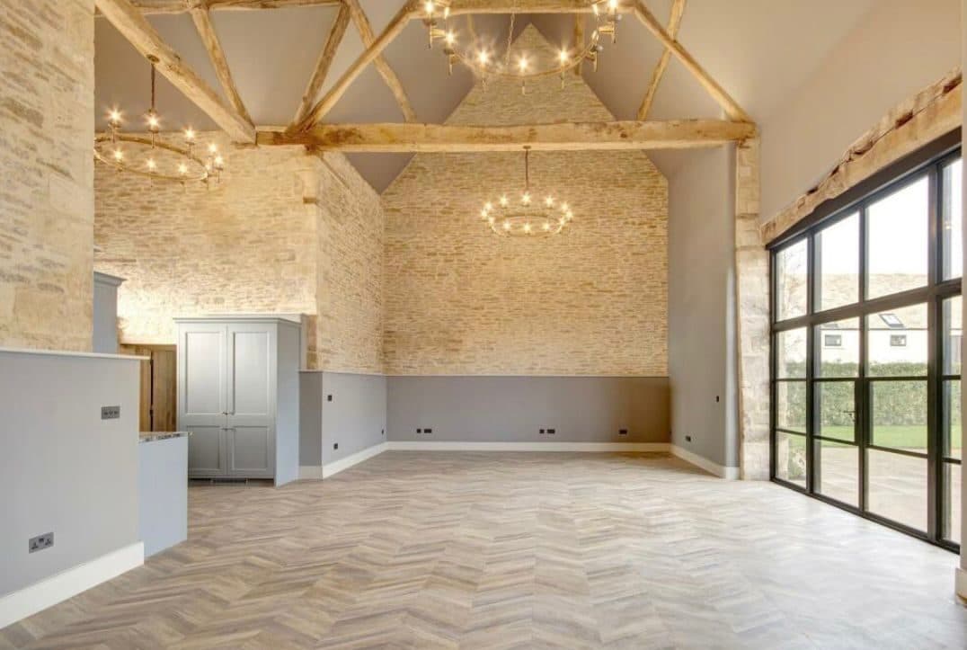 Cotswold barn conversion living space wired throughout, with exposed oak trusses, feature lighting and full-height steel windows