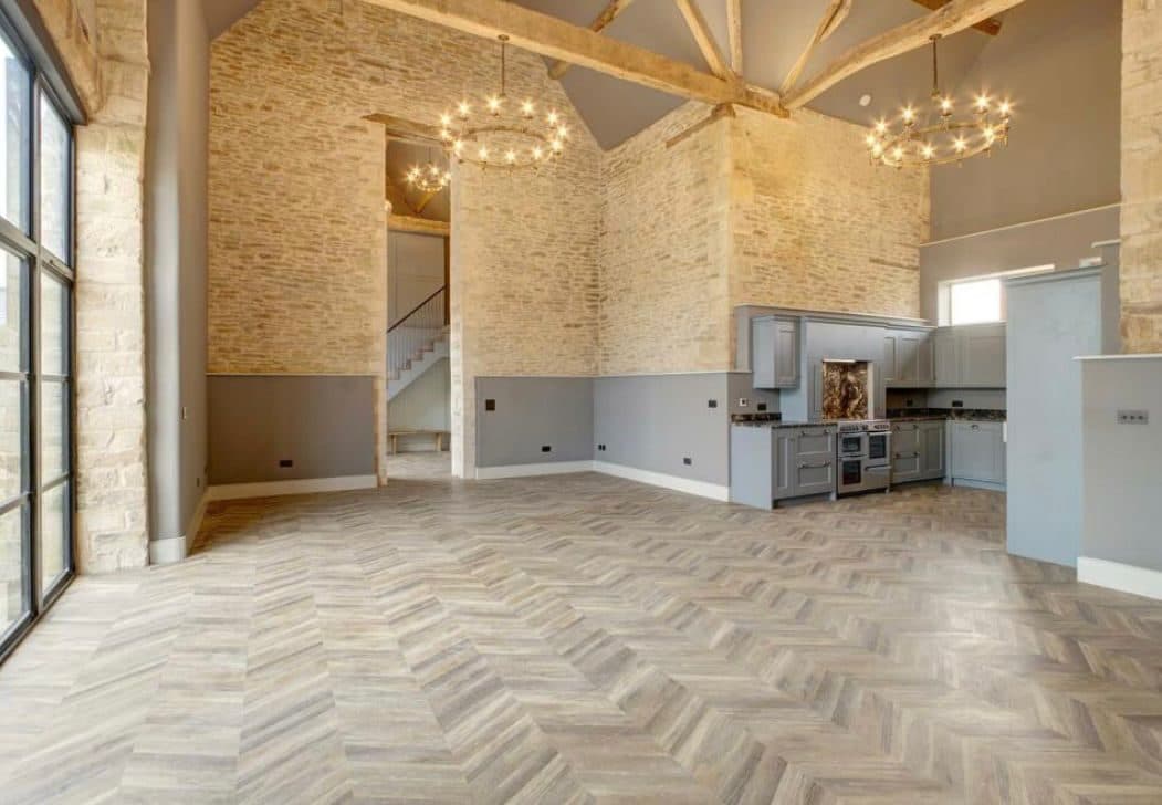Barn conversion kitchen and dining space with ring chandeliers, herringbone floor and a grey shaker kitchen
