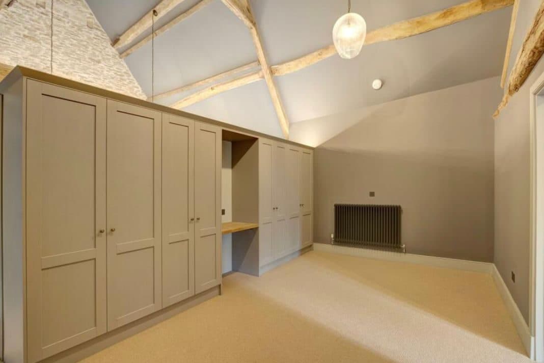 Bedroom with fitted wardrobes, exposed oak beams and a pendant light