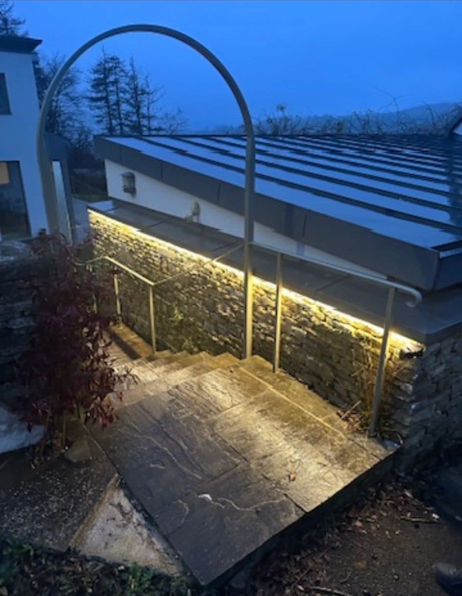 External stone steps and retaining wall lit with a concealed LED strip and handrail lighting