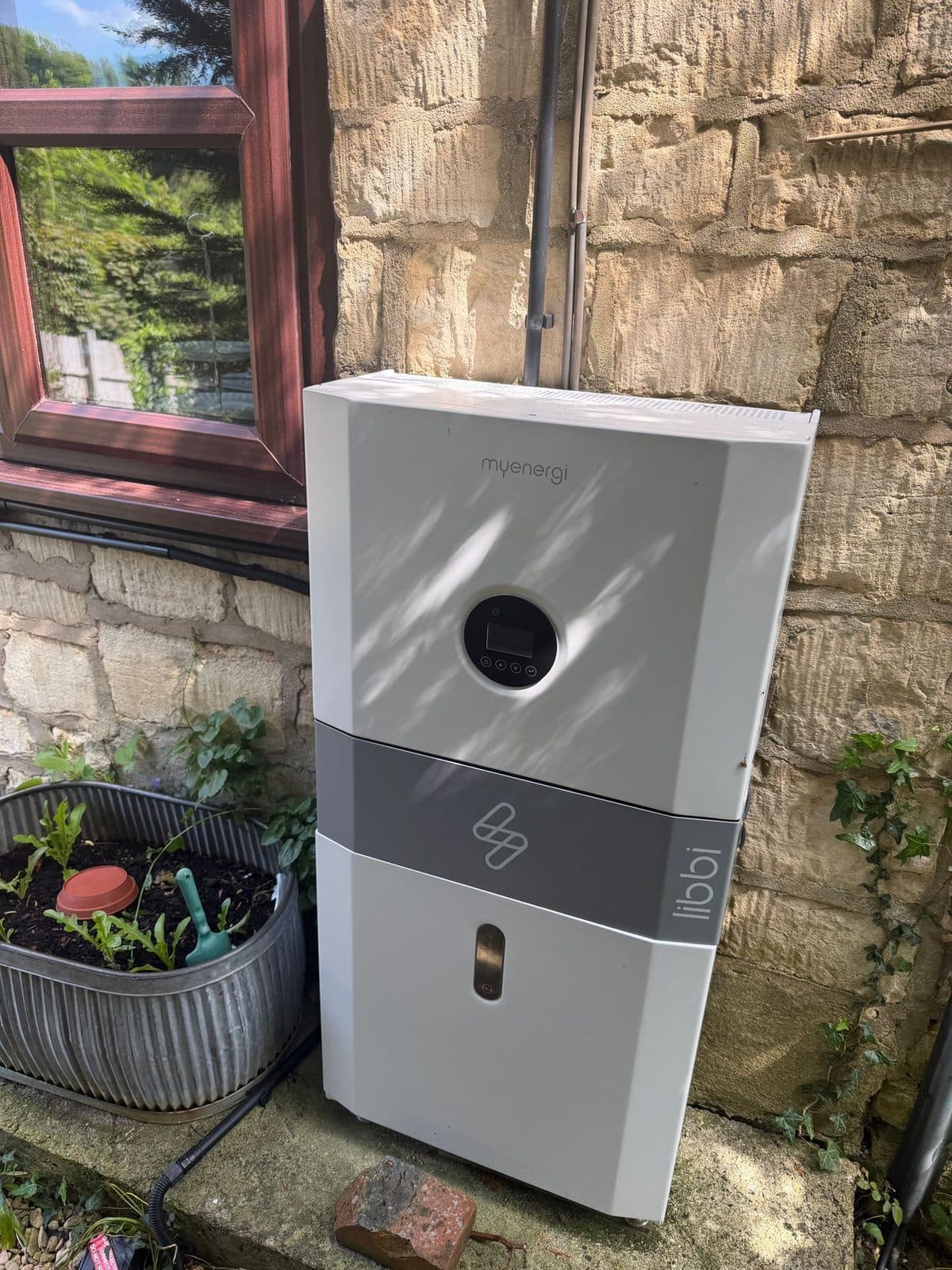 myenergi libbi home battery storage unit installed against a stone wall
