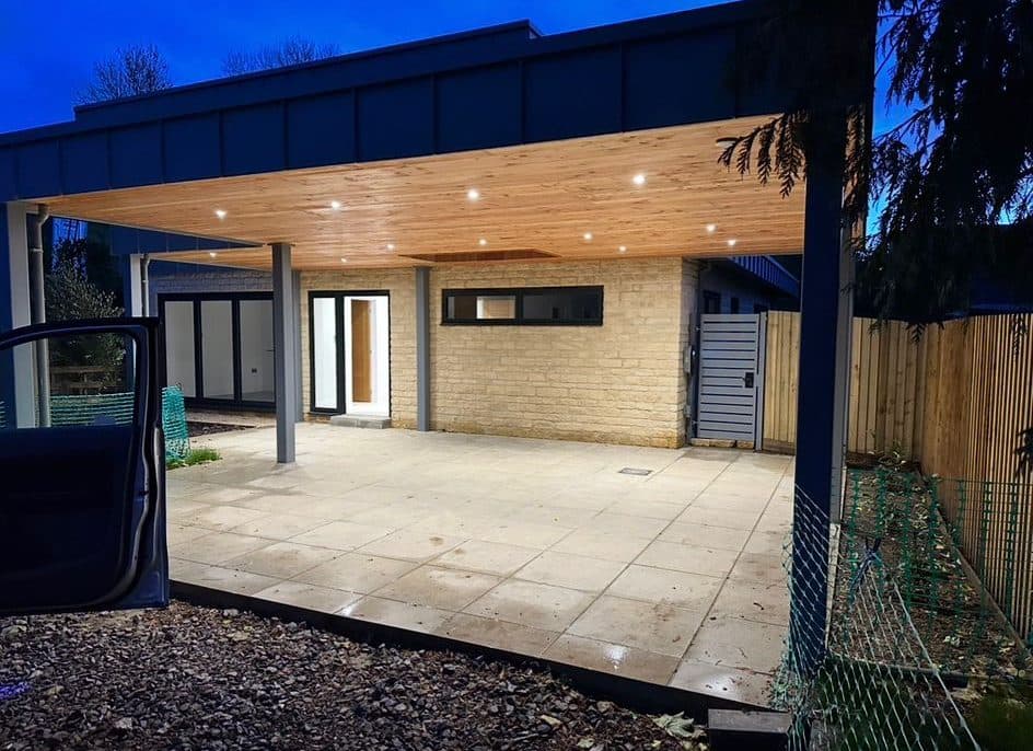 Timber-lined carport canopy fitted with recessed downlights, lit at dusk
